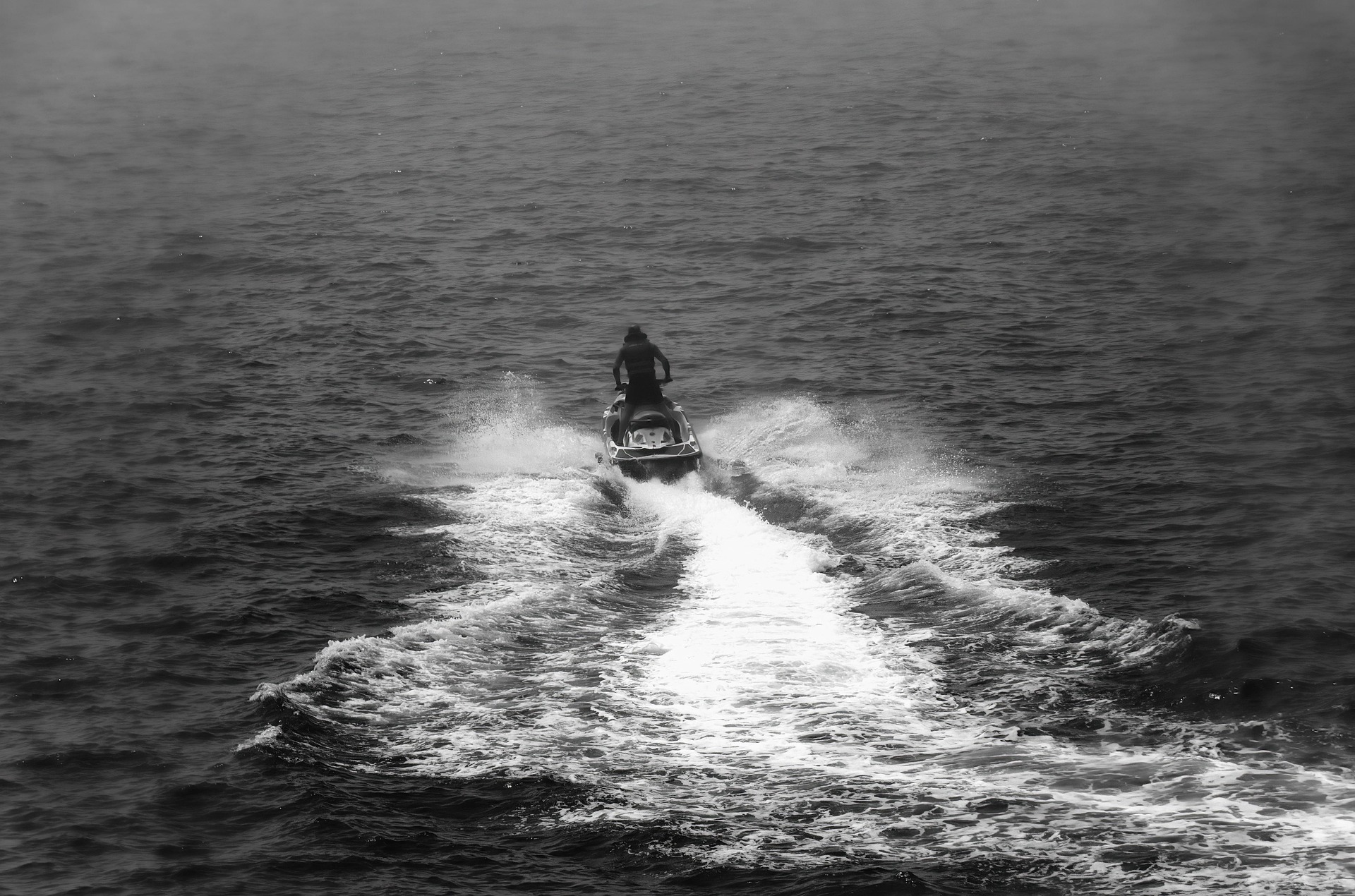 Aerial view of a man riding a motorboat in Sag Harbor, showcasing a Hamptons Boat Rental experience along the sandy beach
