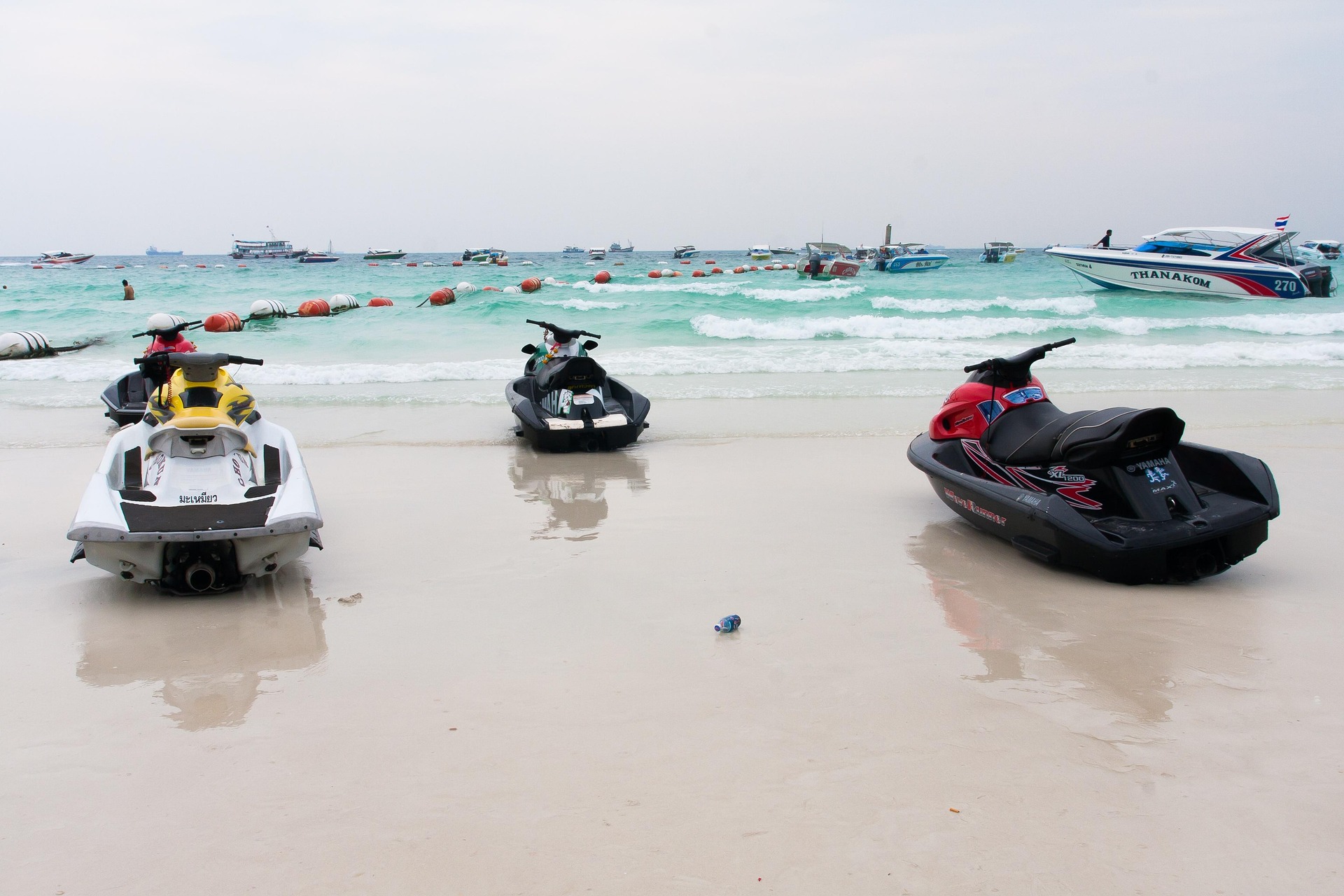 Speed boats and luxury yachts docked along the shoreline of a sandy beach in Sag Harbor, perfect for a Hamptons Boat Rental